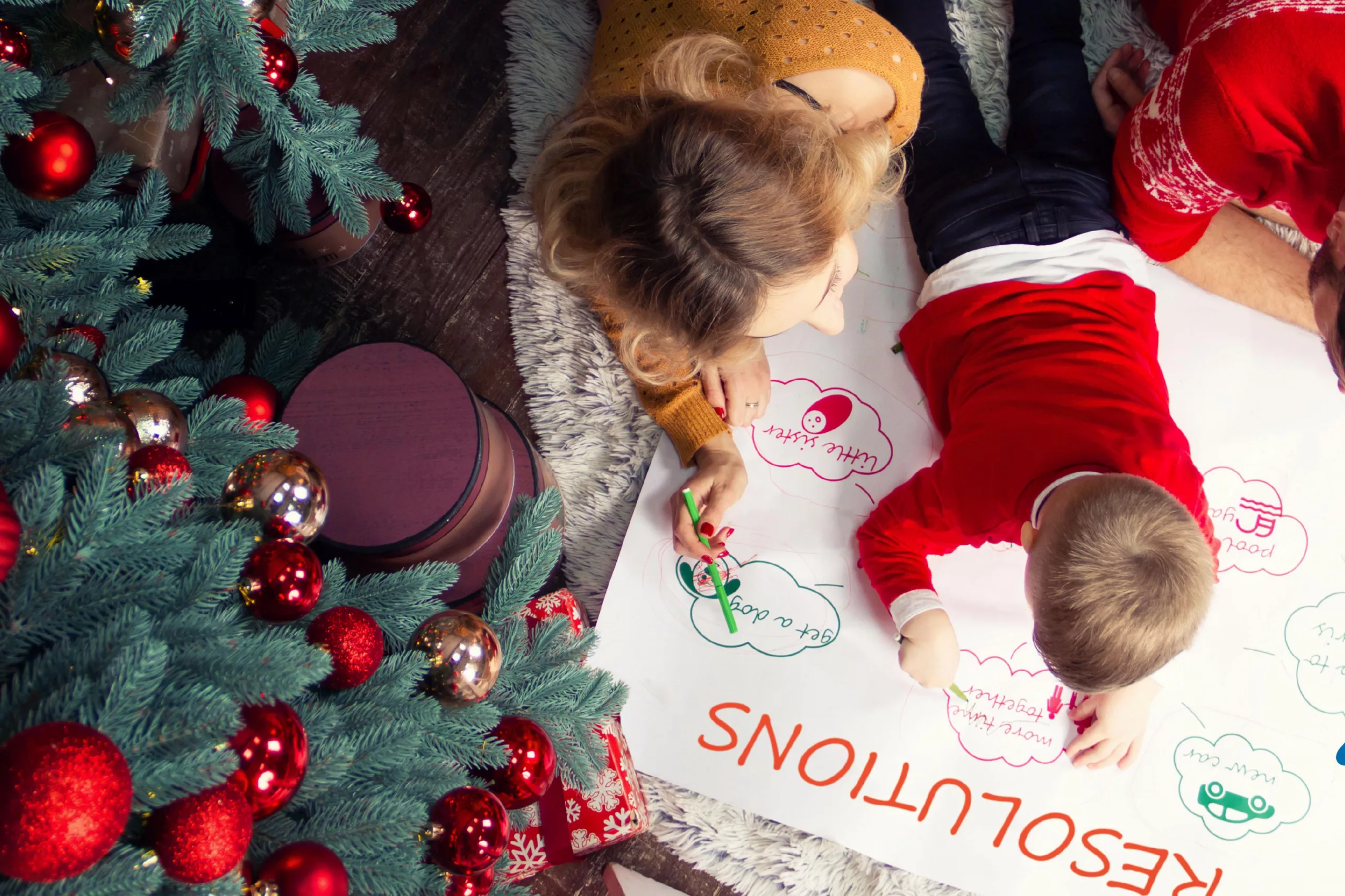 Family writing New Years resolutions under a Christmas tree