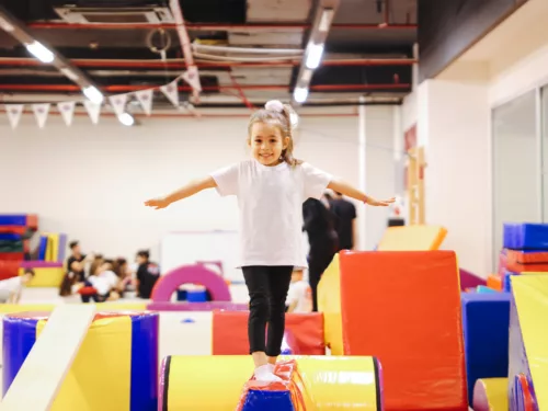 youth-programs-overview-gymnastics A girl stands atop a tumbling cushion in a gymnastics arena.