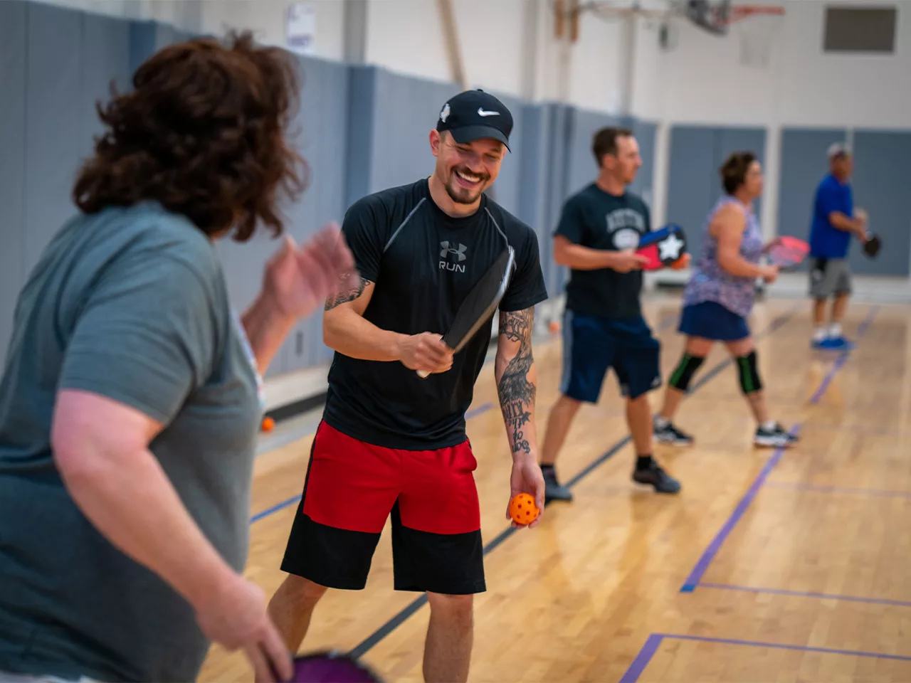 Coed pickleball players smile at one another between sets.