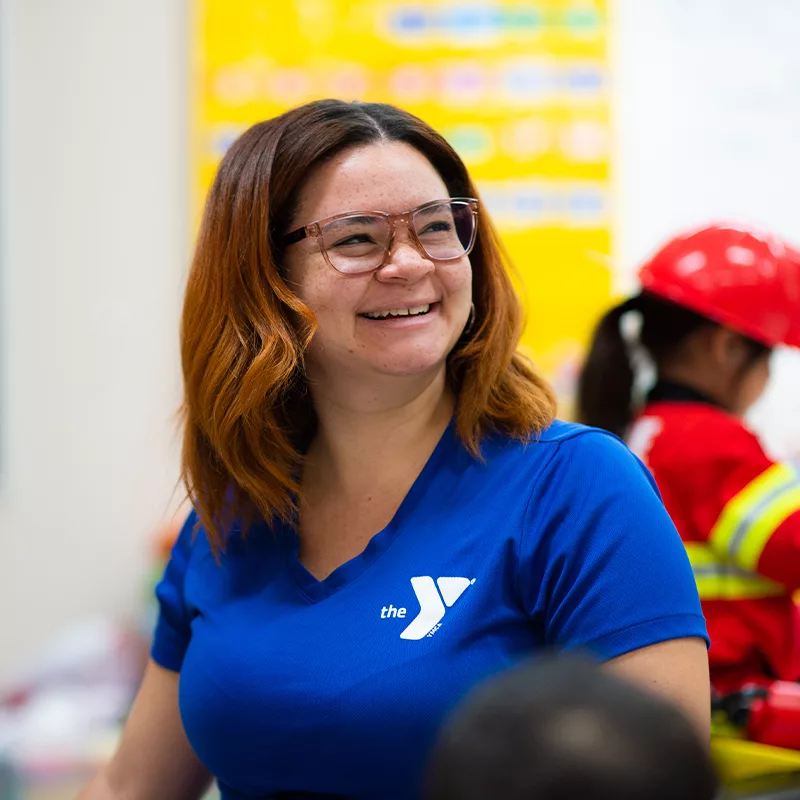 A YMCA employee smiles in a colorful room