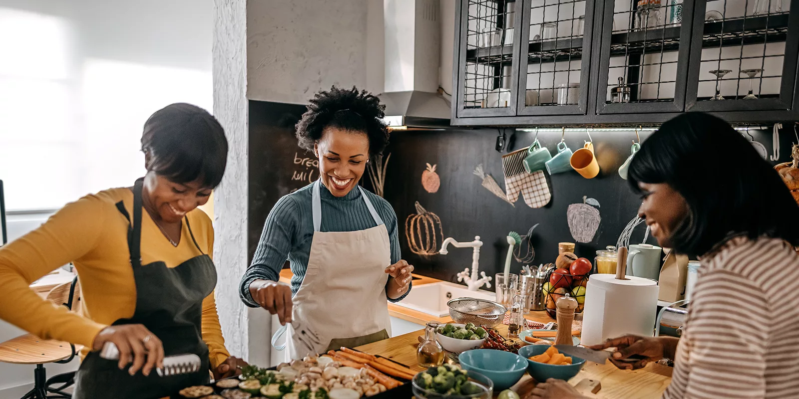 Family members stand around a countertop in a kitchen preparing a meal.