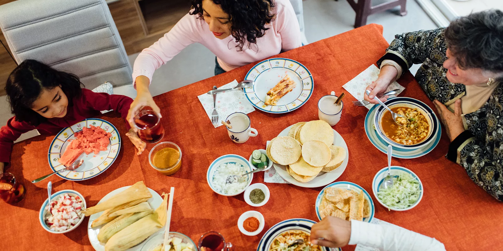 A table is set with food and a family gathers around to eat.
