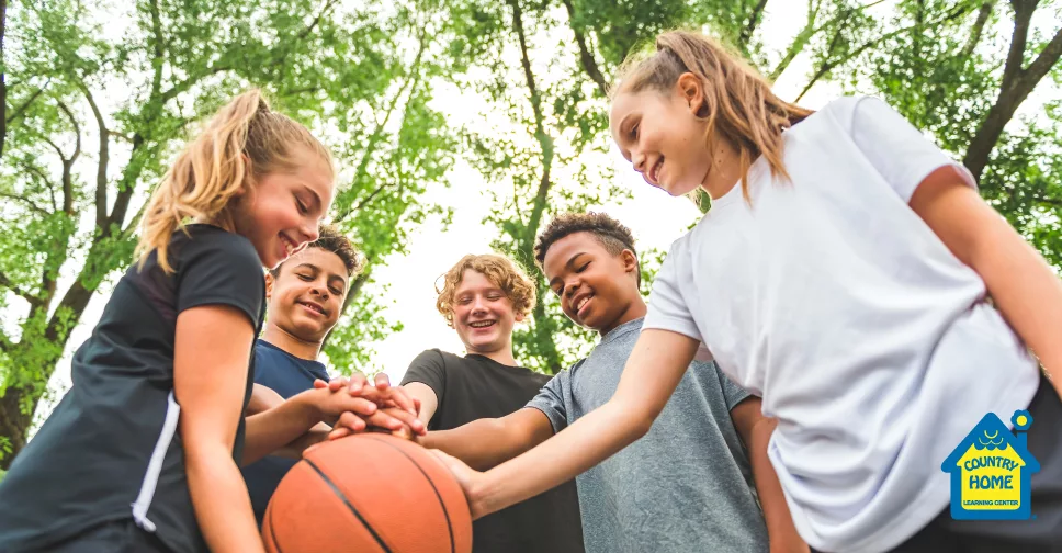 5 kids smile outdoors while holding a basketball