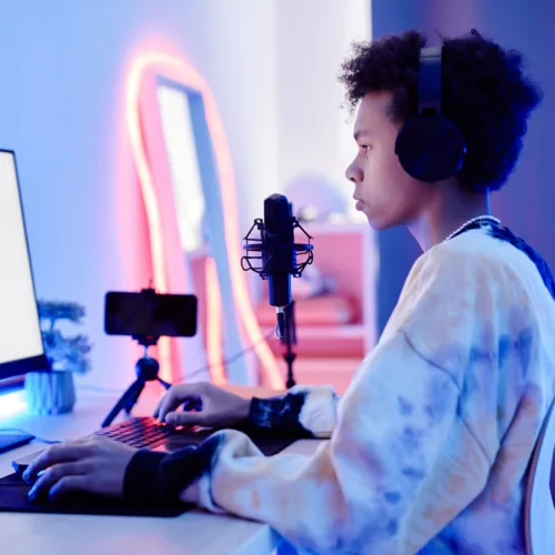 A teen sits in a recording booth with lots of tech around.