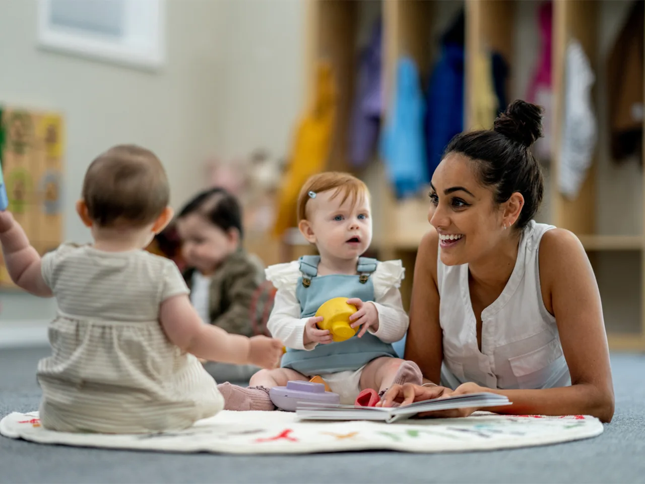 a woman lies on a floor playing with babies