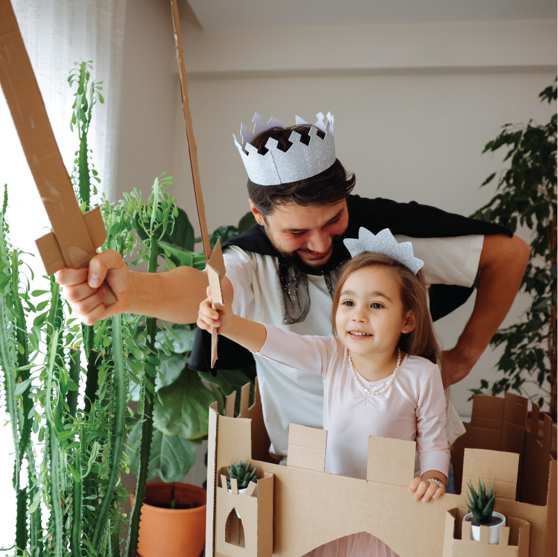pretendplay5 A father and his child dressed up in crowns and holding up cardboard swords pretend play