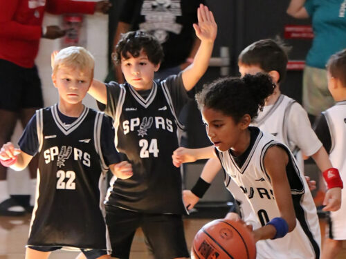 Kids in Spurs jerseys play youth basketball at the Greater Austin YMCA, building teamwork and confidence on the court.