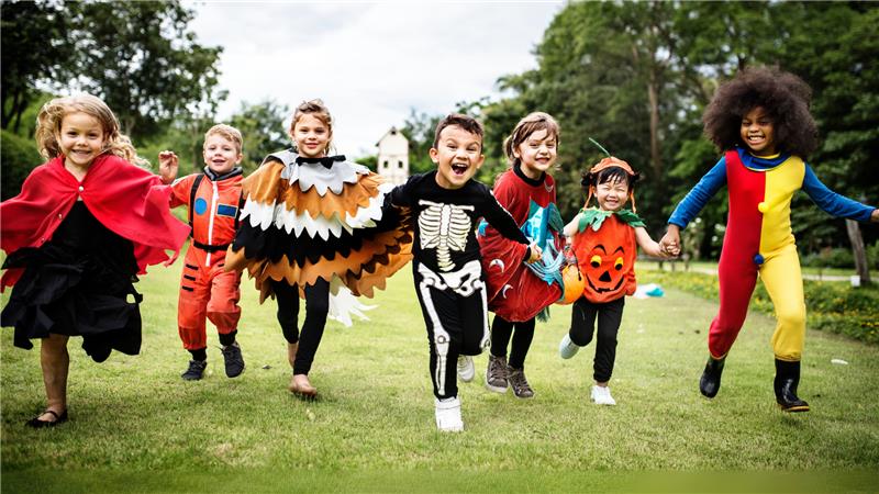 Kids running in field dressed in halloween costumes