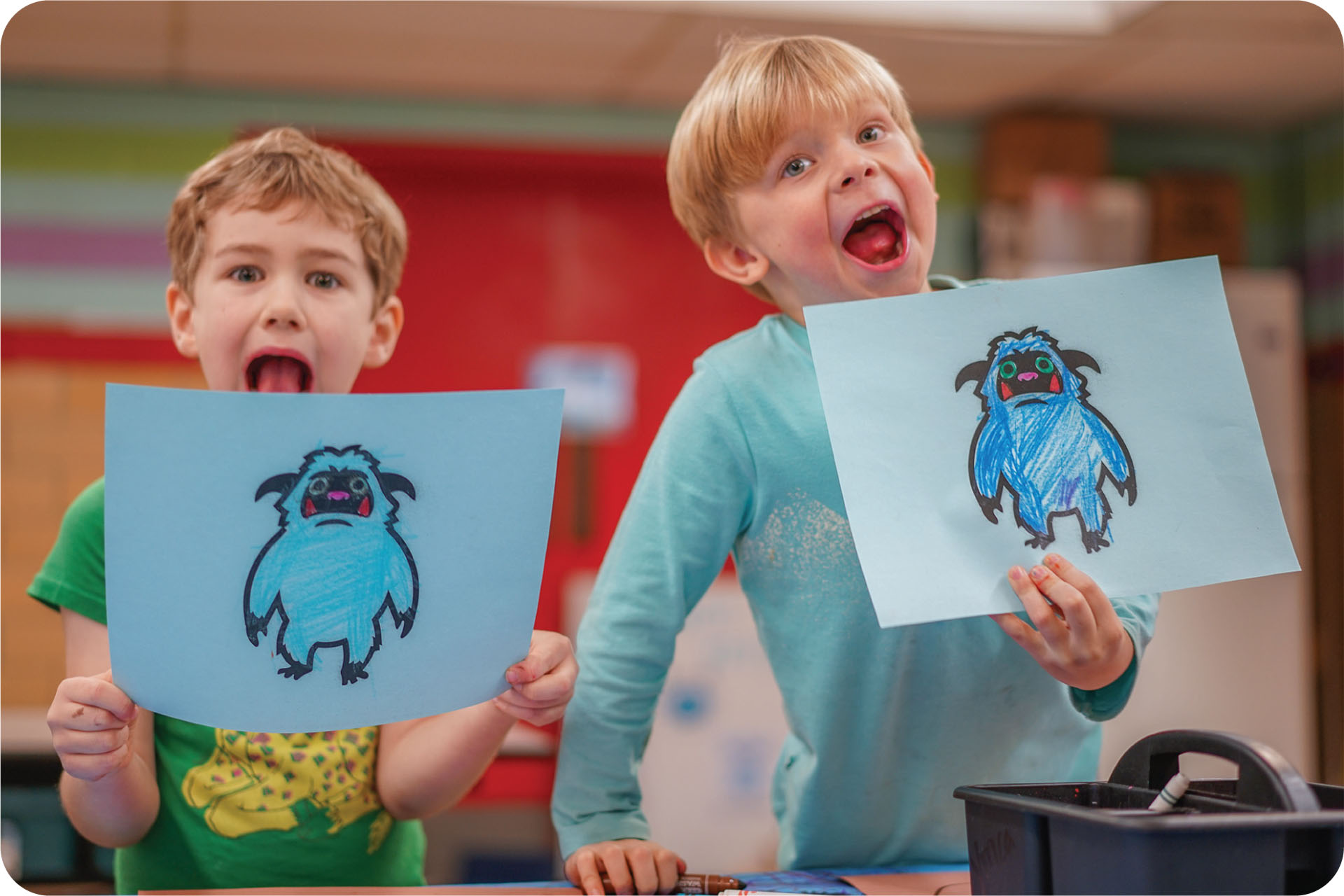 Two boys holding up their artwork of winter yetis growl in a silly manner