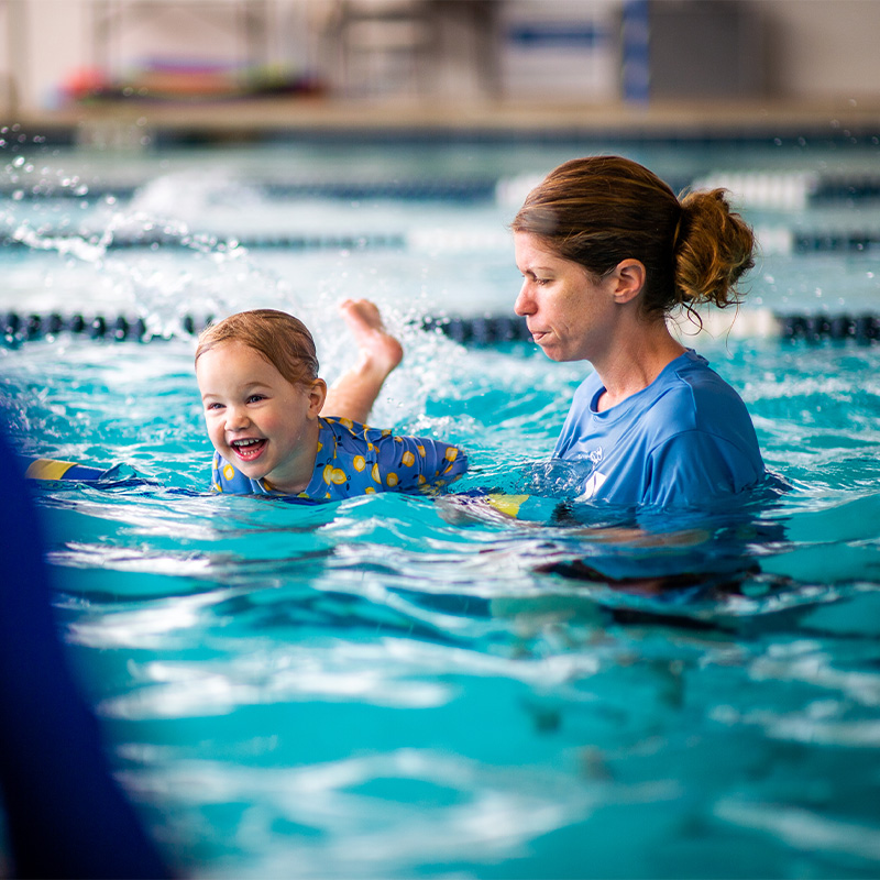 A young child participates in a swim class to learn swimming movement.