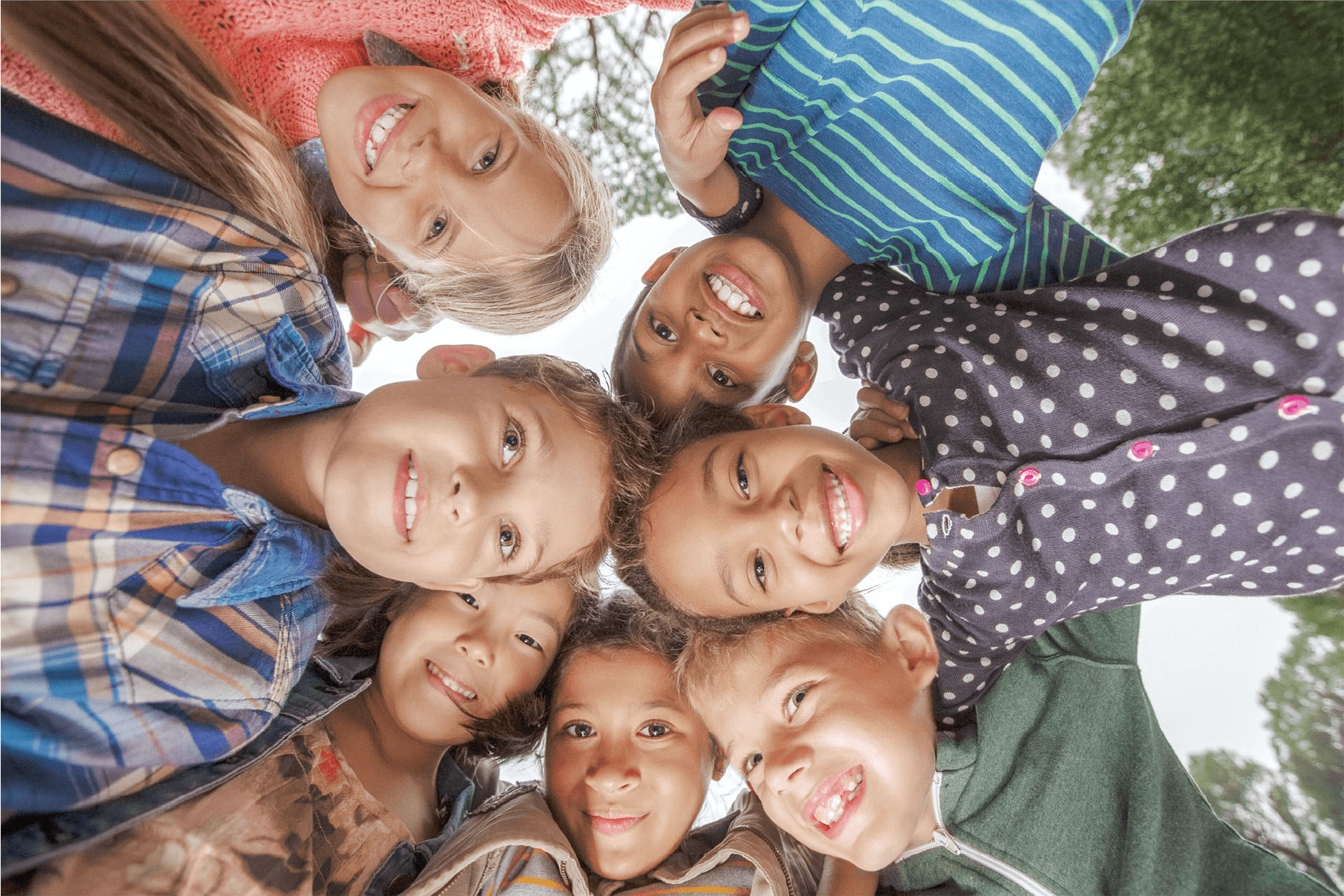 A group of kids stand in a circle looking down to the camera