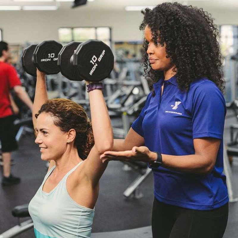 trainer teaching woman proper form for lifting weights