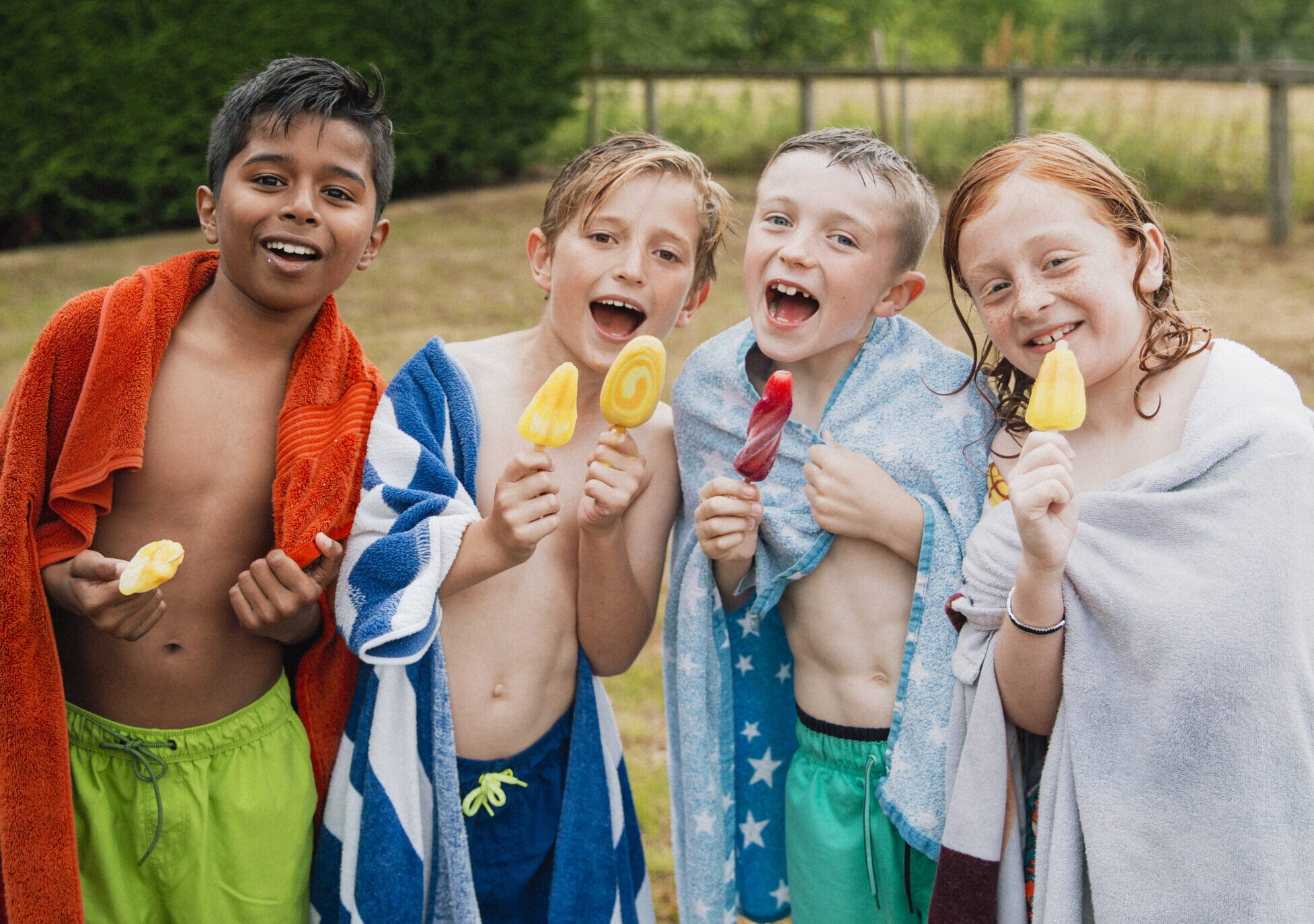group of children eating popsicles after going in the pool