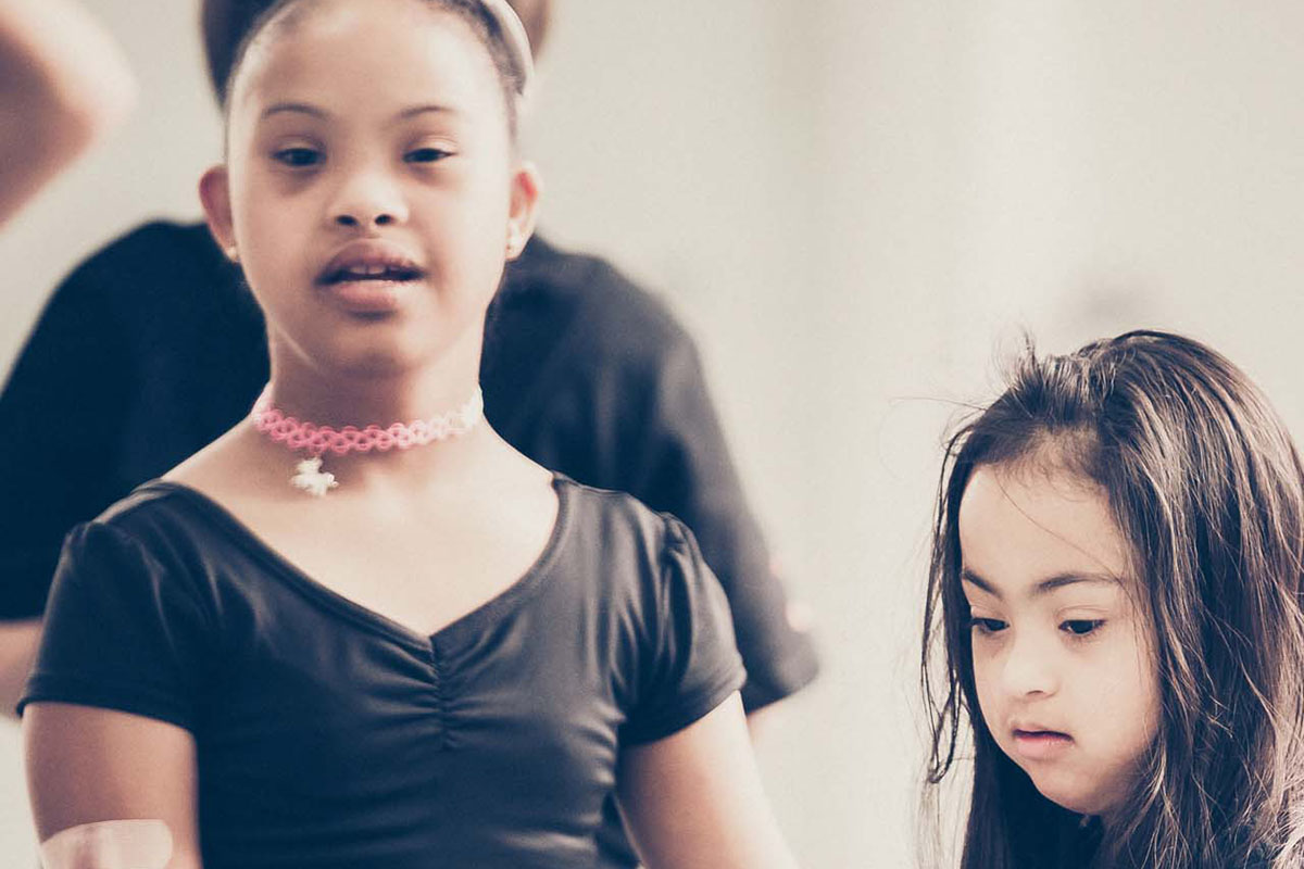 Two young females with trisomy-21 are in ballet outfits