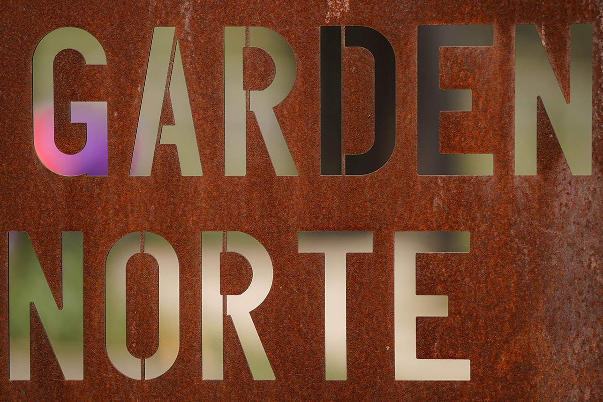A rusted metal sign features lazer-cut letters that read “Garden Norte”