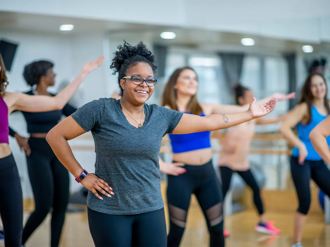 A woman gestures with her hands on her hips during a dance class.