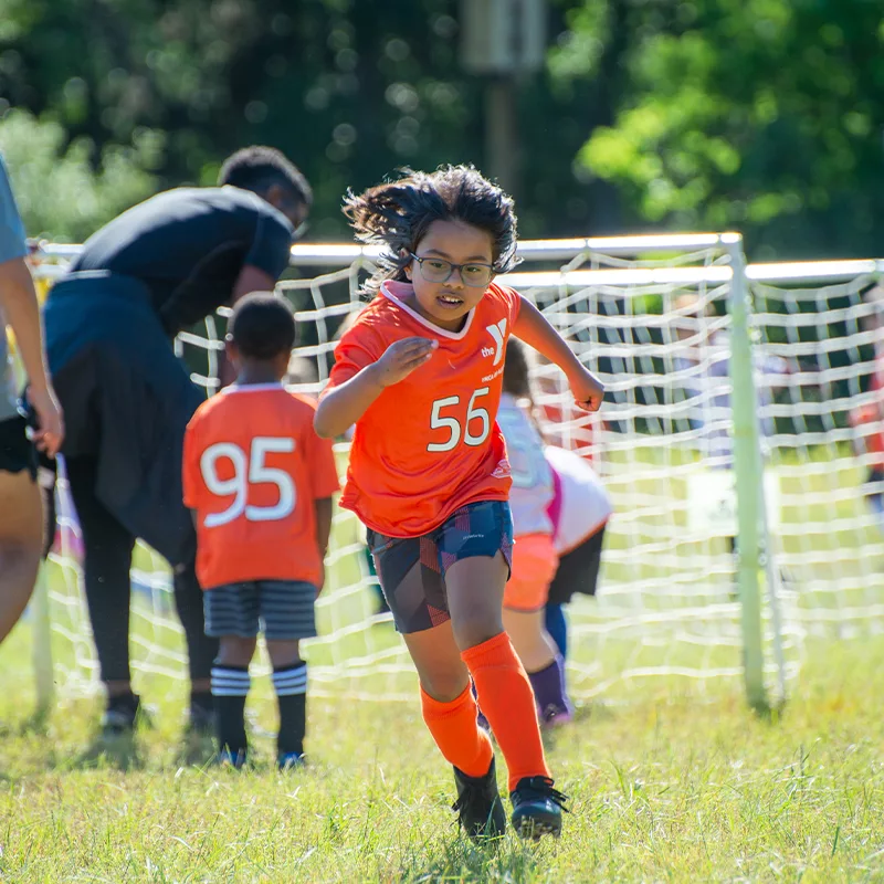 A child runs with determination on a soccer pitch.