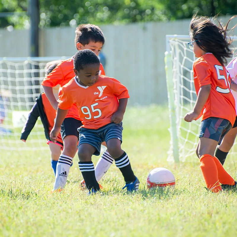 Children wearing orange jerseys play a game of soccer.