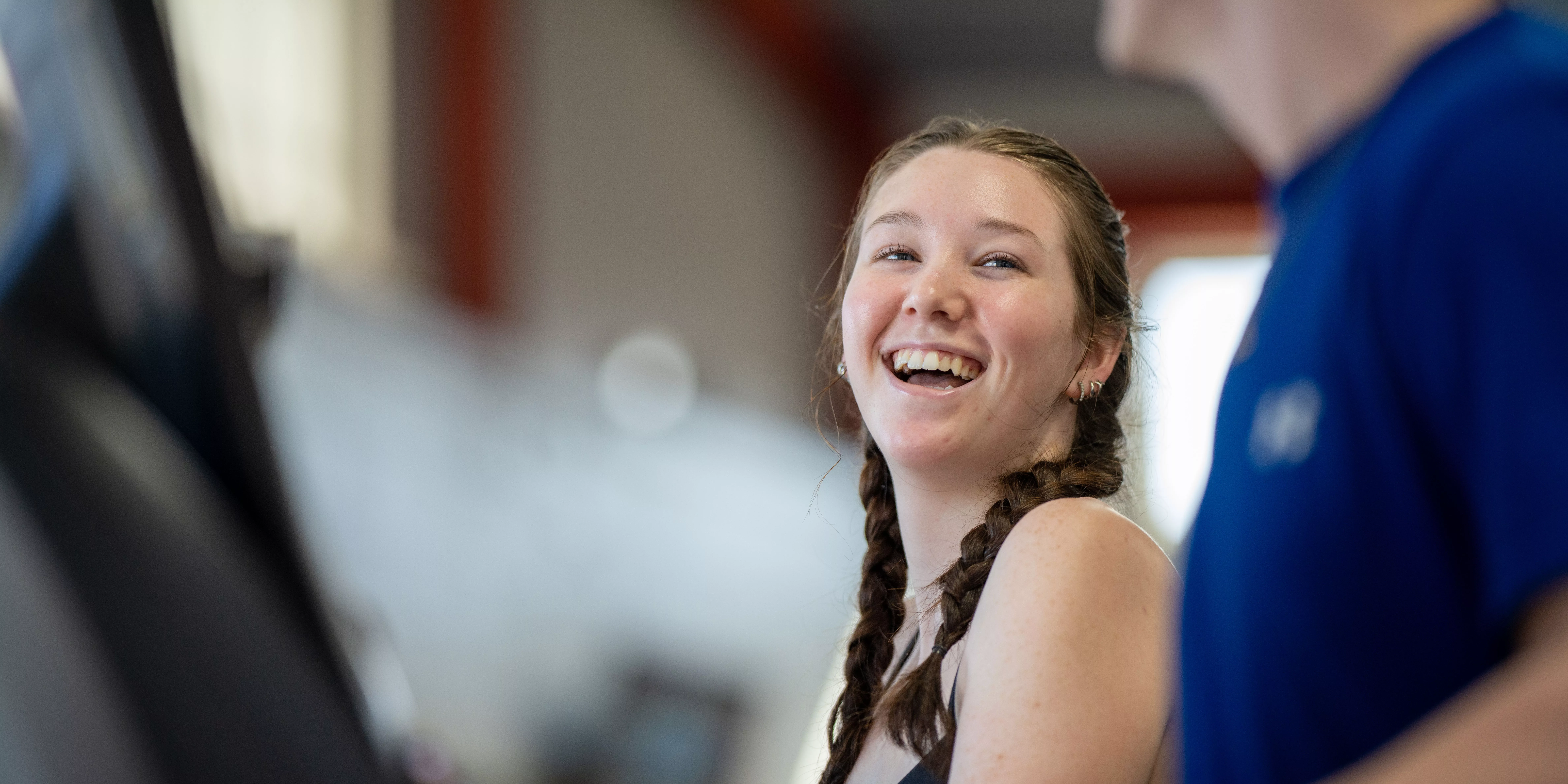 A young woman smiles across a treadmill