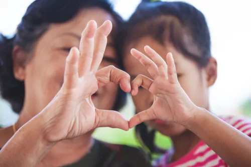 Grandmother and little girl making heart shape with hands together with love