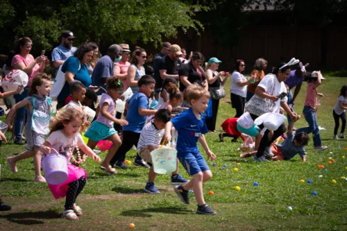 Kids and parents run towards the field of easter eggs to hunt